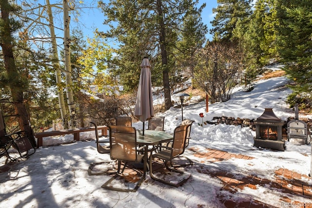 snow covered patio featuring exterior fireplace