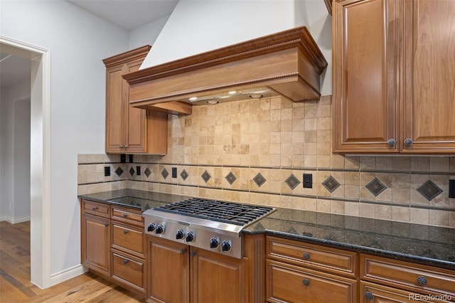 4364 Chateau Ridge Ln, Castle Rock, CO 80108 - kitchen with wall chimney range hood, stainless steel gas cooktop, and brown cabinetry