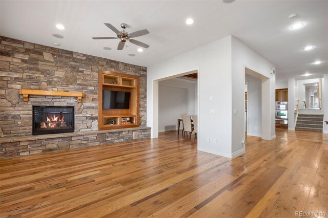 4364 Chateau Ridge Ln, Castle Rock, CO 80108 - unfurnished living room with hardwood / wood-style floors, a stone fireplace, a ceiling fan, recessed lighting, and stairs