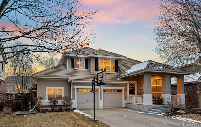 view of front of property with a garage, a tiled roof, concrete driveway, and stucco siding