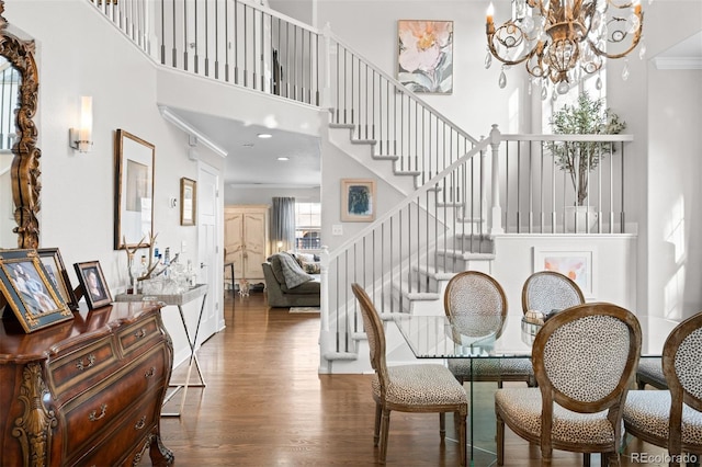 dining room featuring stairway, ornamental molding, wood finished floors, a high ceiling, and a chandelier