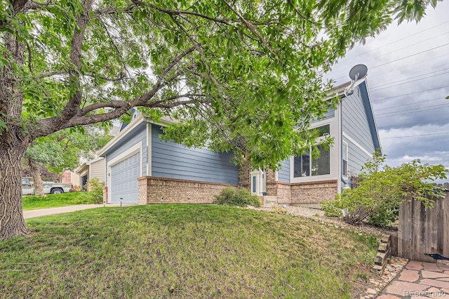 view of side of home with driveway, brick siding, a lawn, and fence