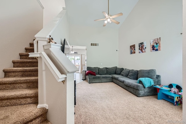 carpeted living room with ceiling fan, high vaulted ceiling, stairway, and visible vents