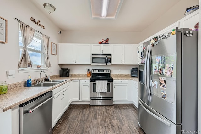 kitchen with light countertops, appliances with stainless steel finishes, dark wood-type flooring, white cabinetry, and a sink