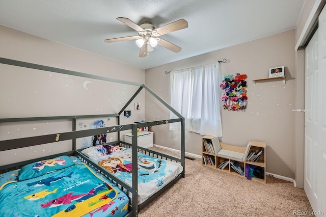 carpeted bedroom with ceiling fan, baseboards, and a closet