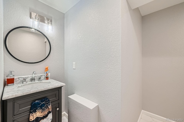 bathroom featuring a textured wall, vanity, and baseboards