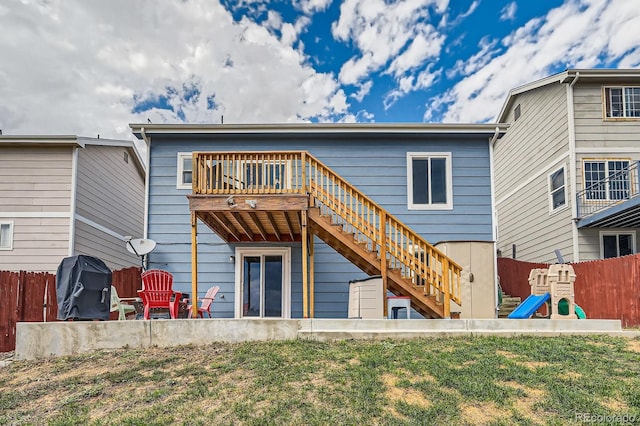 rear view of property featuring a yard, a playground, fence, and stairway