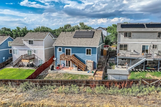 back of property featuring solar panels, a fenced backyard, a residential view, stairs, and a wooden deck