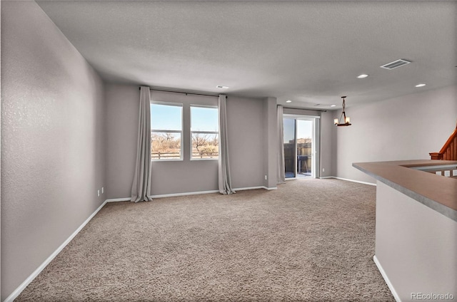 carpeted spare room with plenty of natural light and a textured ceiling