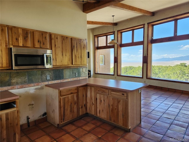 kitchen with backsplash, hanging light fixtures, beam ceiling, dark tile patterned flooring, and kitchen peninsula