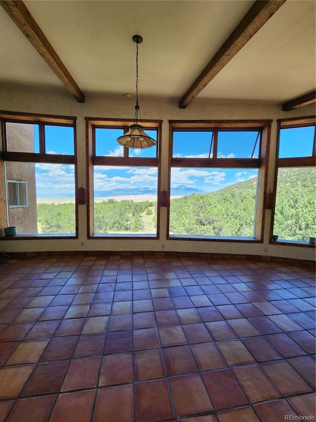 unfurnished dining area with beam ceiling and dark tile patterned flooring