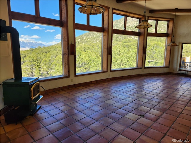 interior space with a towering ceiling, a wood stove, tile patterned flooring, and a healthy amount of sunlight