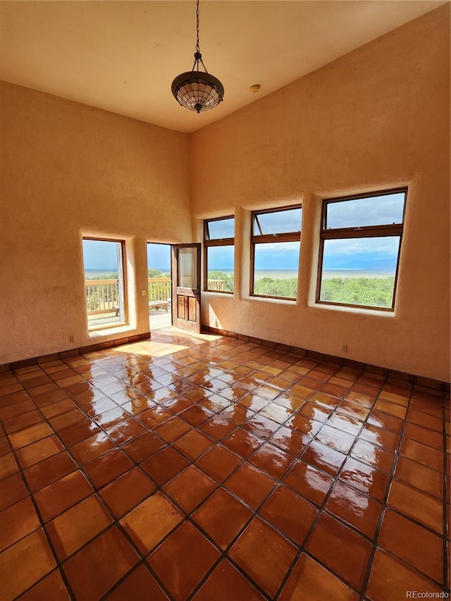 tiled empty room with a healthy amount of sunlight and a high ceiling