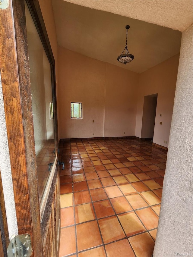 interior space with light tile patterned flooring, a textured ceiling, and lofted ceiling