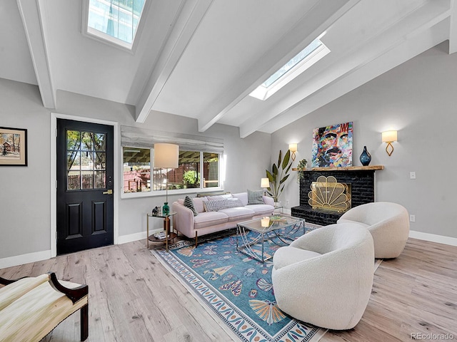 living room featuring vaulted ceiling with skylight, light hardwood / wood-style flooring, and a brick fireplace