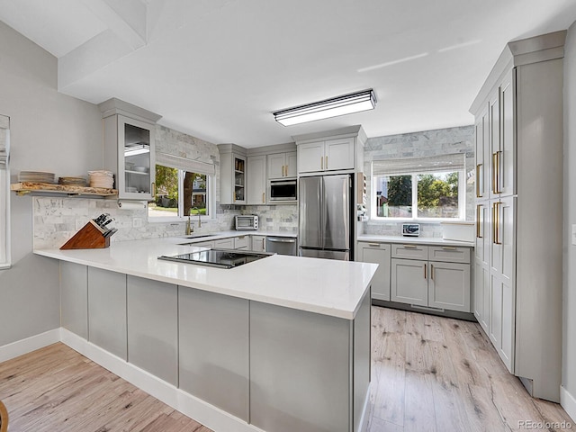 kitchen with light hardwood / wood-style floors, kitchen peninsula, stainless steel appliances, and sink