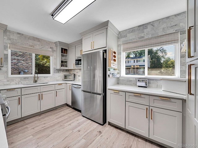 kitchen with gray cabinets, sink, light hardwood / wood-style flooring, and stainless steel appliances