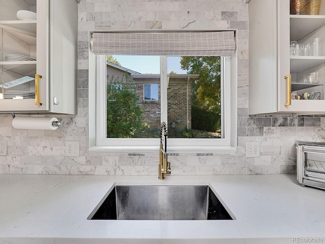 details with sink, light stone counters, and backsplash