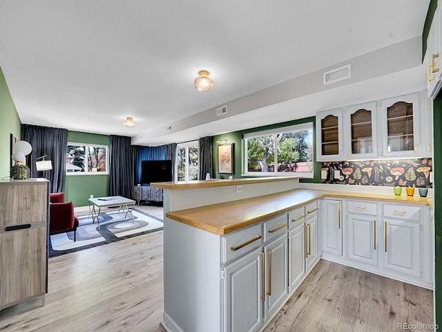 kitchen with kitchen peninsula, white cabinets, and light wood-type flooring