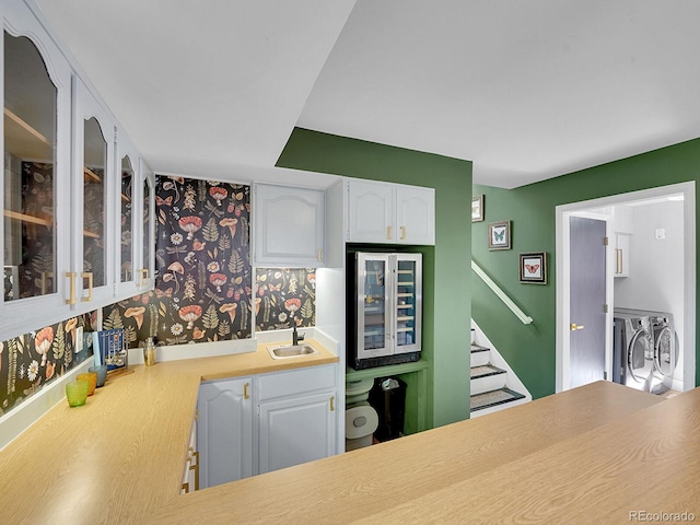 kitchen with sink, white cabinetry, separate washer and dryer, and beverage cooler