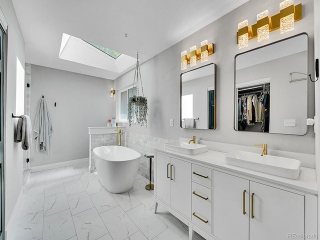 bathroom with vanity, a tub to relax in, and a skylight