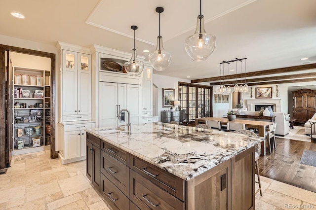 kitchen featuring white cabinetry, stone tile floors, light stone countertops, and glass insert cabinets
