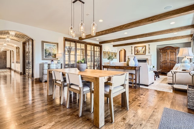 dining room with beamed ceiling, light wood-style flooring, arched walkways, and recessed lighting
