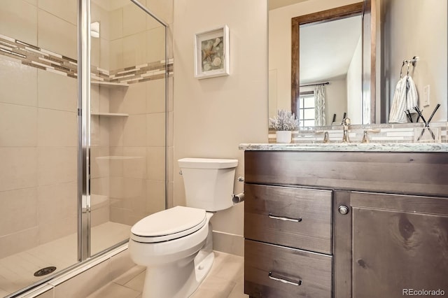 bathroom featuring tile patterned flooring, vanity, toilet, and a stall shower