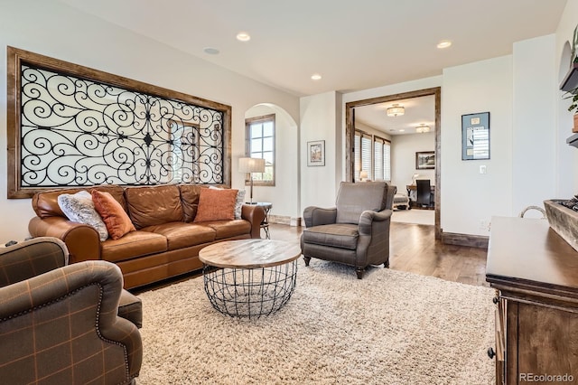 living room featuring baseboards, wood finished floors, arched walkways, and recessed lighting