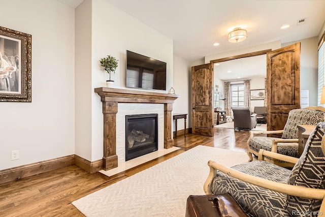living area featuring baseboards, wood finished floors, visible vents, and a fireplace