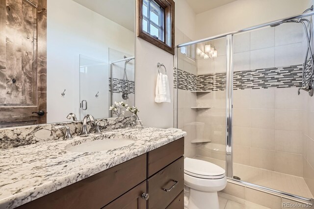 bathroom featuring tile patterned flooring, toilet, vanity, and a stall shower