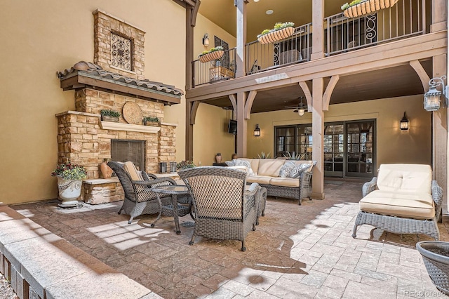 view of patio featuring an outdoor living space with a fireplace, a balcony, and a ceiling fan