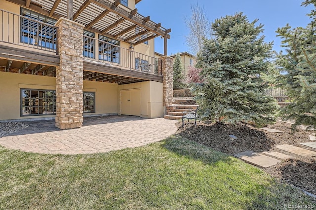 back of house with a patio area, a balcony, and stucco siding