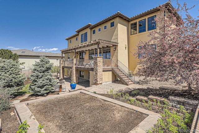 rear view of property with stairway, a pergola, stucco siding, a patio area, and a deck