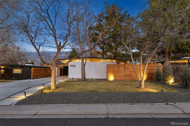 view of front of home with a carport, concrete driveway, a front lawn, and fence