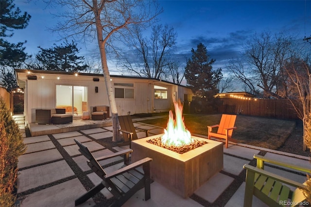 patio terrace at dusk featuring a fire pit and fence