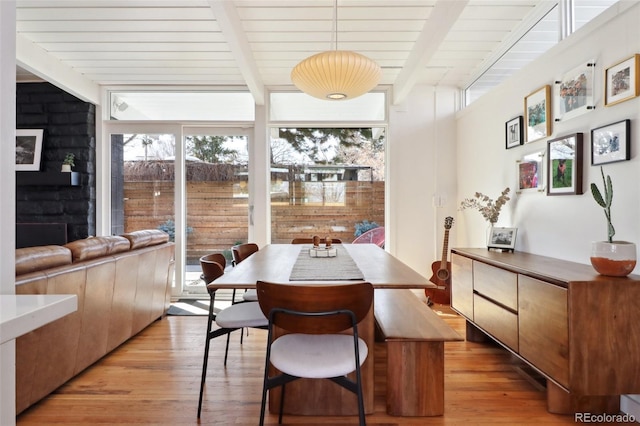 dining space featuring beam ceiling, light wood-style flooring, wood ceiling, and expansive windows