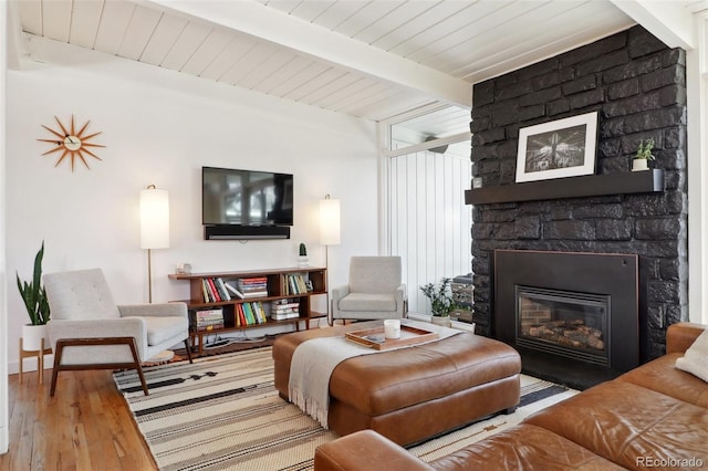 living area featuring beamed ceiling, wood ceiling, wood finished floors, and a fireplace