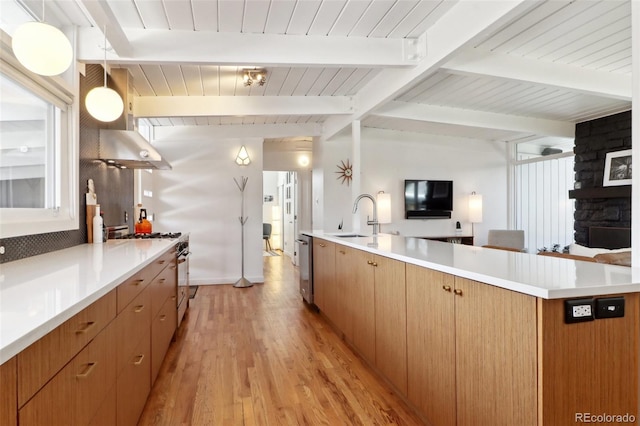 kitchen featuring gas stove, a sink, light countertops, open floor plan, and light wood-type flooring