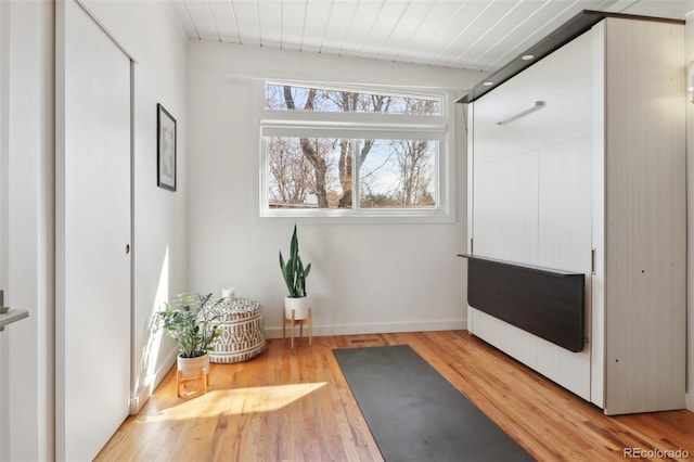 workout room with baseboards and light wood-type flooring