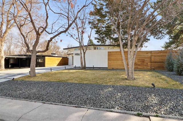 view of front facade featuring a front yard, an outbuilding, driveway, and fence