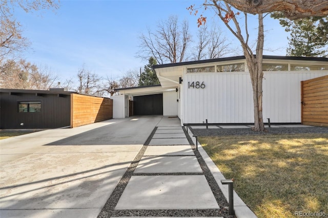 view of property exterior featuring an attached garage, fence, and driveway