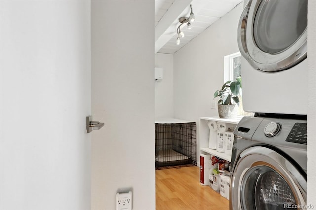 clothes washing area with light wood finished floors, laundry area, and stacked washer and clothes dryer