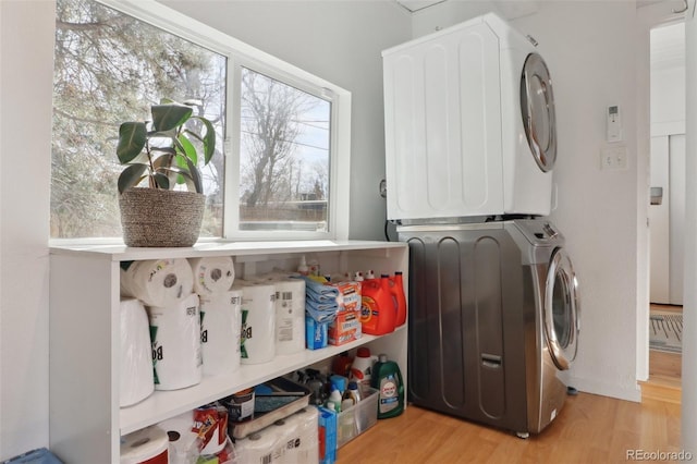 laundry area featuring laundry area, stacked washer / dryer, and light wood-style floors