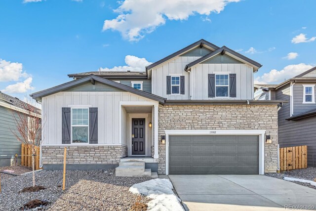 view of front of home with fence, driveway, stone siding, and board and batten siding