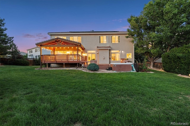 10085 Charissglen Ct, Highlands Ranch, CO 80126 - back of house at dusk with a hot tub, roof mounted solar panels, stucco siding, a wooden deck, and a fenced backyard