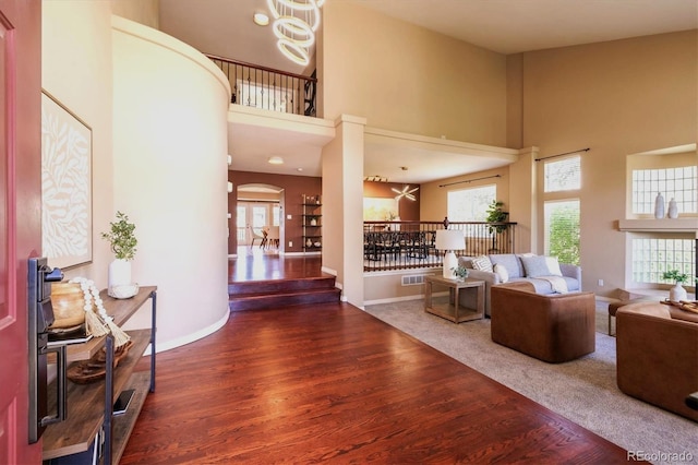 10085 Charissglen Ct, Highlands Ranch, CO 80126 - living area with wood finished floors, a towering ceiling, healthy amount of natural light, and arched walkways