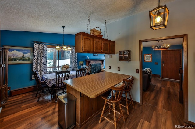 kitchen with baseboard heating, a textured ceiling, decorative light fixtures, and a brick fireplace