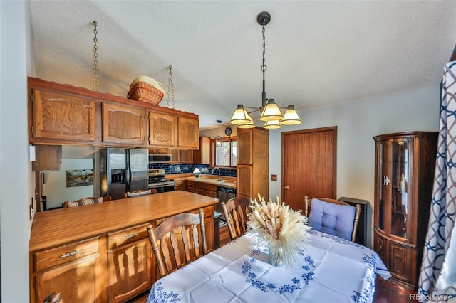 dining space with sink, a textured ceiling, and an inviting chandelier