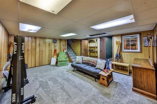 rec room featuring a paneled ceiling, wooden walls, and carpet floors